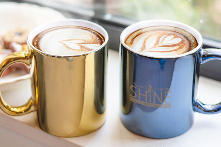 Two branded coffee cups with latte foam art